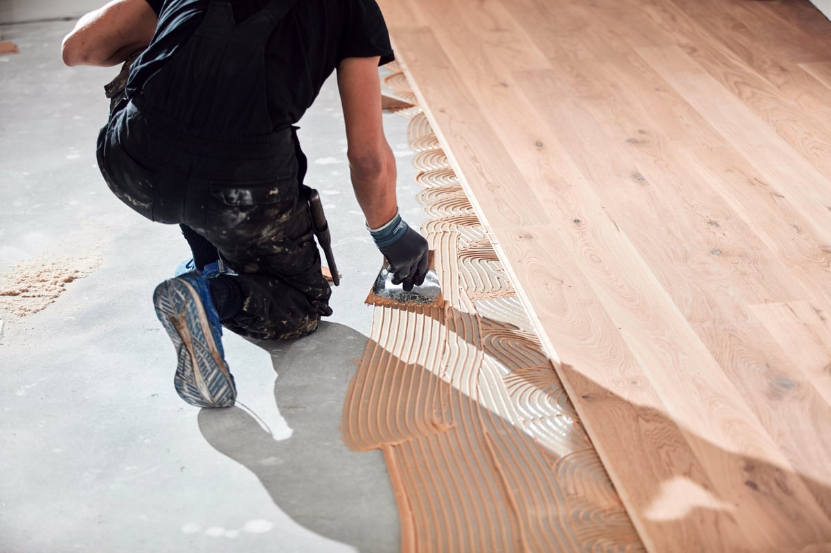 Worker installing laminate flooring in a home