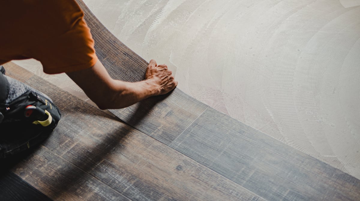 Worker installing luxury vinyl plank flooring