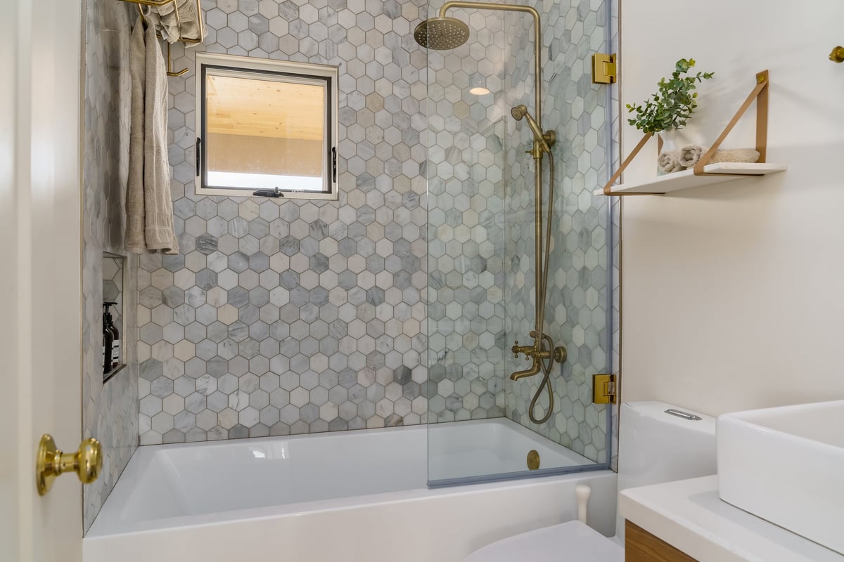 Modern renovated bathroom with tiled shower and brass fixtures